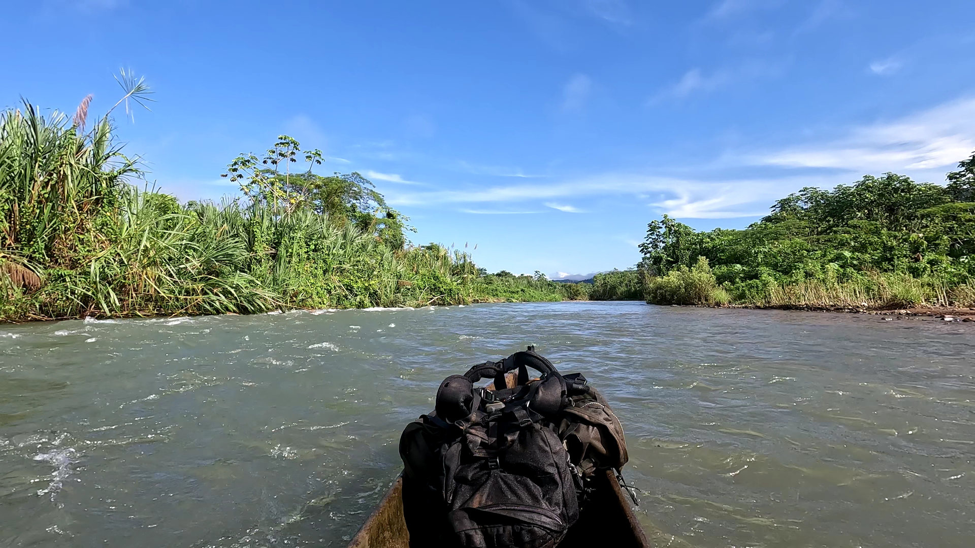 Dugout canoe loaded with packs moving up a Darién river